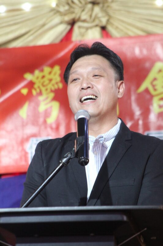 One person is photographed in front of a red, gold and yellow Chinese New Year banner during the Taiwanese New Year Celebrations.