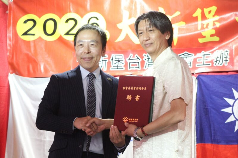 Two people are photographed in front of a red, gold and yellow Chinese New Year banner during the Taiwanese New Year Celebrations.