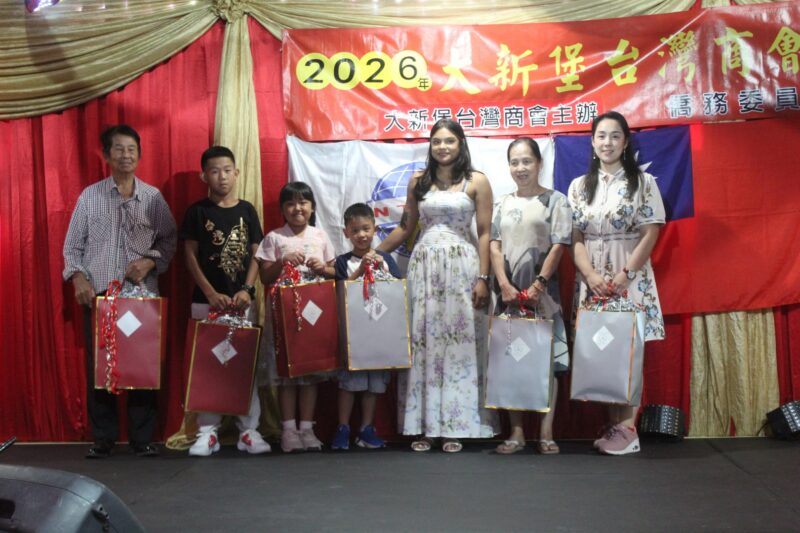 A group of people are photographed in front of a red, gold and yellow Chinese New Year banner during the Taiwanese New Year Celebrations.