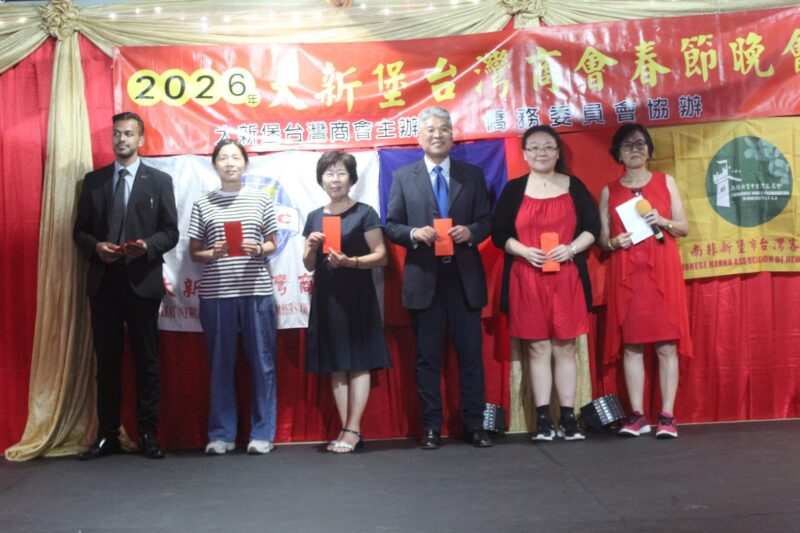 A group of people are photographed in front of a red, gold and yellow Chinese New Year banner during the Taiwanese New Year Celebrations.