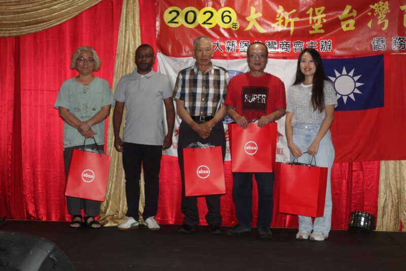 A group of people are photographed in front of a red, gold and yellow Chinese New Year banner during the Taiwanese New Year Celebrations.