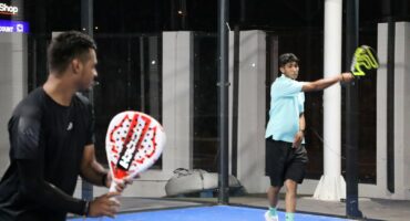 Two players compete during a padel match at night.