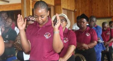 An image of a woman praying alongside other members of Santaco at a prayer service for scholar transport in Vryheid.
