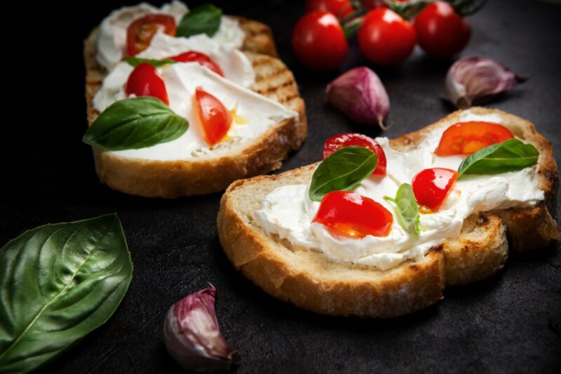 Bruschetta on Garlic Toast with tomatoes and mozzarella cheese on a dark table.