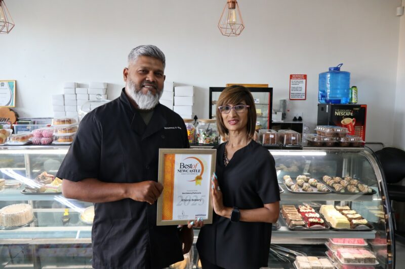 Two people holding an awards certificate for the Best of Newcastle Readers Choice Awards.