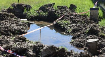 Image of danger tape half covering leaking pipe and hole in Dundee.