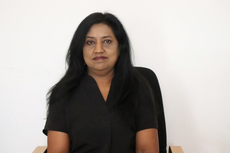 A woman who works at the Newcastle Advertiser dressed in their formal black uniform in front of a white background.