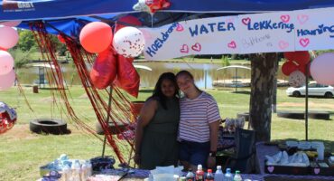 Image of two young girls standing in a stall decorated with Valentine's decor and homemade goods on the table.