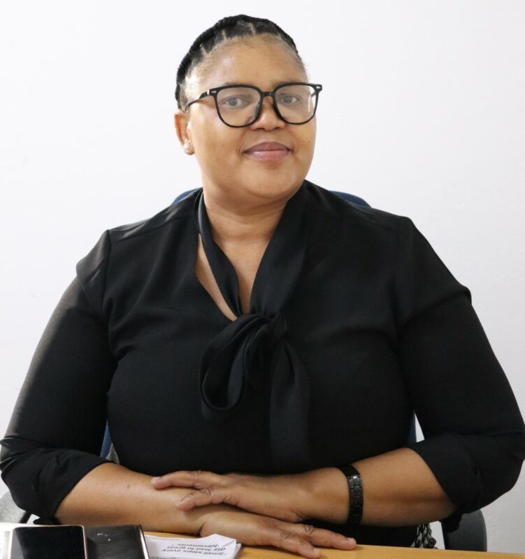A woman who works at the Newcastle Advertiser dressed in their formal black uniform in front of a white background.