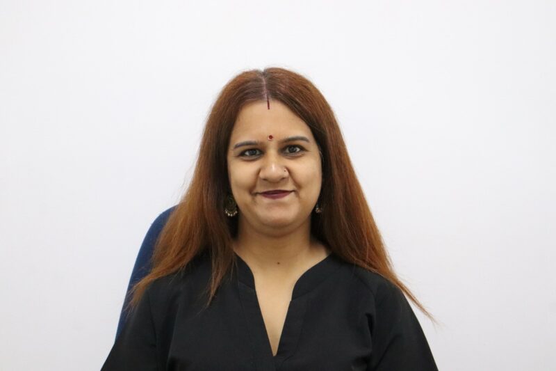A woman who works at the Newcastle Advertiser dressed in their formal black uniform in front of a white background.