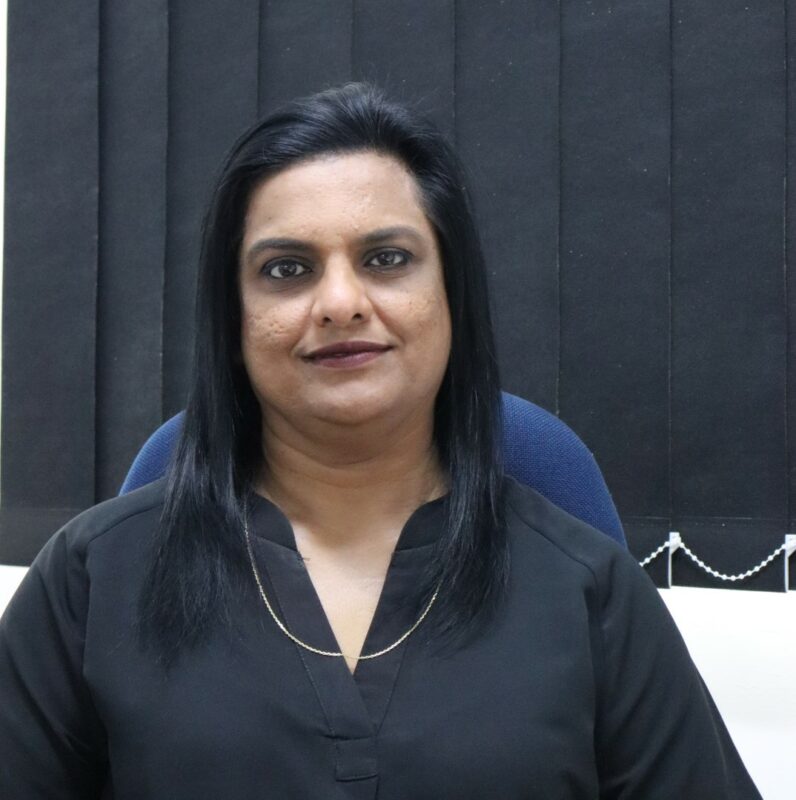 A woman who works at the Newcastle Advertiser dressed in their formal black uniform in front of a white background.