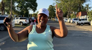 Image of a runner with a huge smile and arms in the air at the end of a fun run.