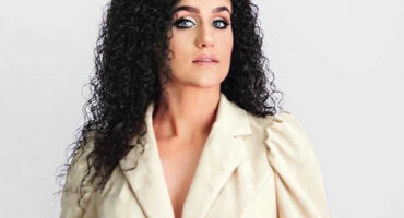 A young beauty pageant contestant poses for a portrait photo in a white blazer suite.