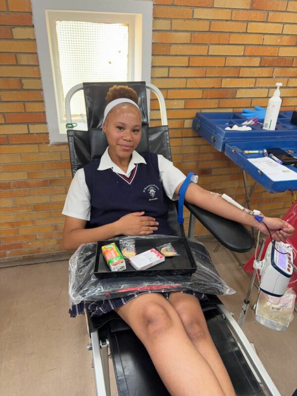 A learner lays in a chair and donates blood at school.