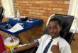 A learner lays in a chair and donates blood at school.
