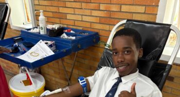 A learner lays in a chair and donates blood at school.