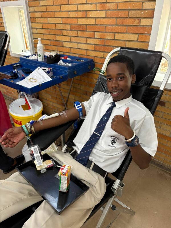 A learner lays in a chair and donates blood at school.