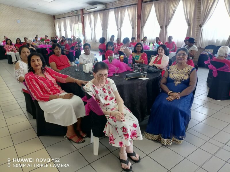 A group of people sitting at their tables posing for a photo while dressed in red and white attire.