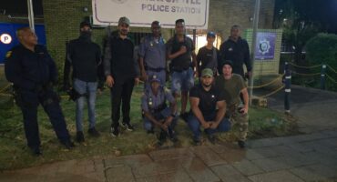 Several men and police officers pose in front of the Newcastle Police Station.