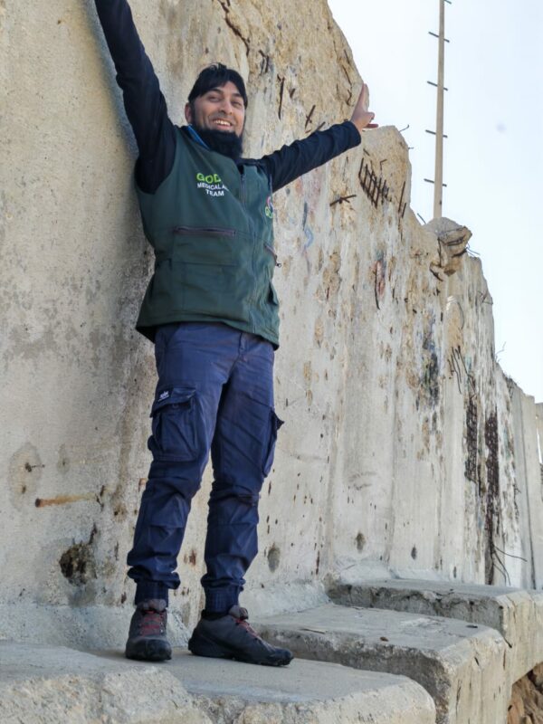Mahomed Zahir Haniff poses for a photo in front of a ruined building while in Gaza. 
