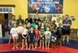 Image of group of young wrestlers and coaches standing in front of the Vryheid Wrestling Club banner.
