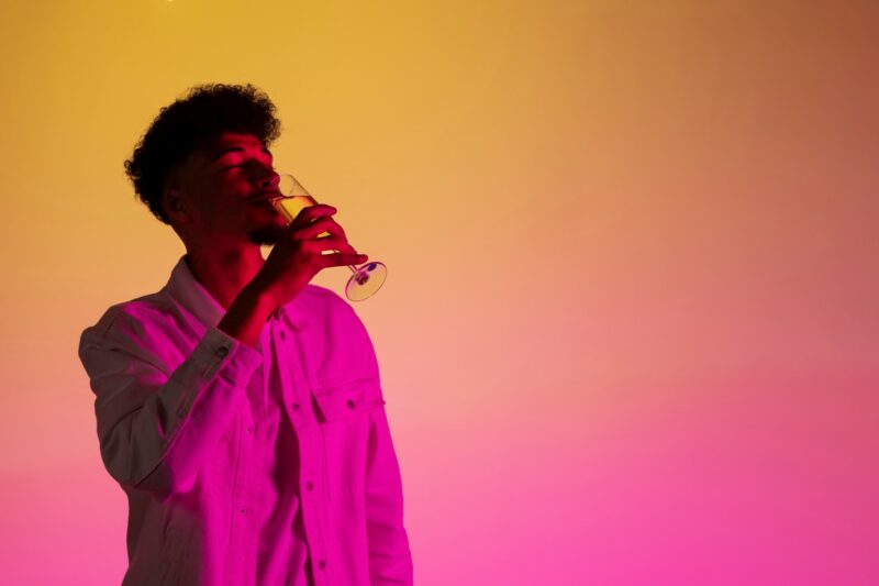 A young man having a drink on his own. pink and yellow tones over the image.