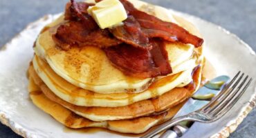 Image of a pile of pancakes with bacon and butter.