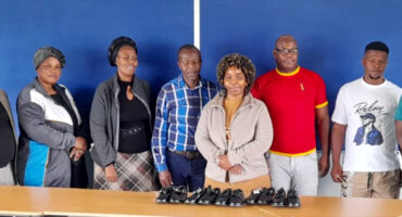 Image of football players donating shoes to needy school children.