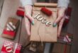 Hands holding a wrapped Valentine’s gift with wooden “love” decoration.