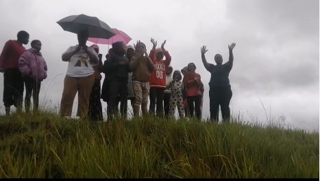 A group of people standing in the rain, rejoicing the rescue of a puppy.