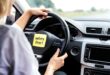 Driver holds steering wheel with safety reminder note