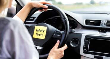 Driver holds steering wheel with safety reminder note