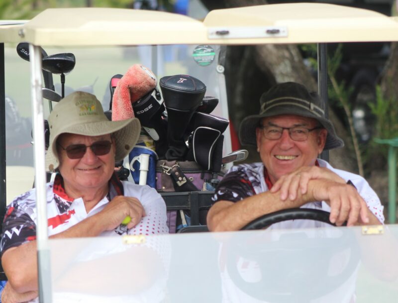 Two golfers posing for a photo in a golf cart at the Newcastle Golf Club.
