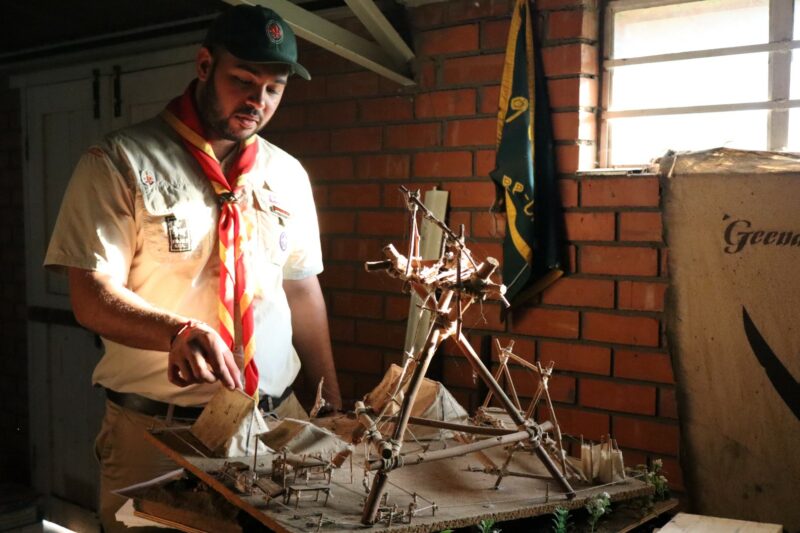 Scout leader examines a handmade camp model inside a Scout hall