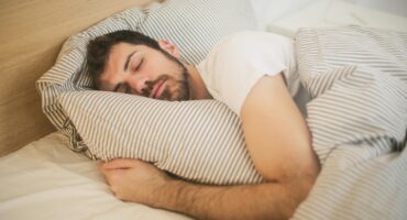 Image of man holding his pillow while sleeping.