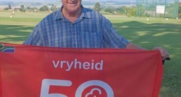 Image of elderly man with a cap and blue shirt holding a red banner with 50 parkrun.