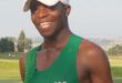 Image of a runner with a white cap and green shirt and a huge smile.