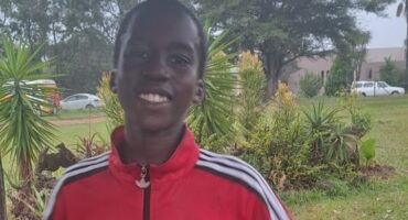 Image of a young parkrunner in a red jacket and with a big smile.