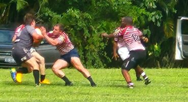 Image of a rugby player with ball in hand while another defends.