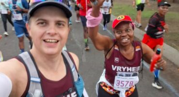 Image of a runner taking a selfie with his co-runner in the background.