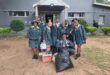 Image of Vryheid High School learners in green and yellow uniforms in front of Risen Son School.