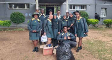 Image of Vryheid High School learners in green and yellow uniforms in front of Risen Son School.