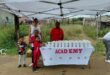 Grown-ups and children are photographed standing next to a table, while handing out food parcels in Siyahlala.