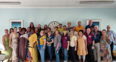 A group of people are photographed wearing blue and yellow attire in support of Down Syndrome Awareness Day.