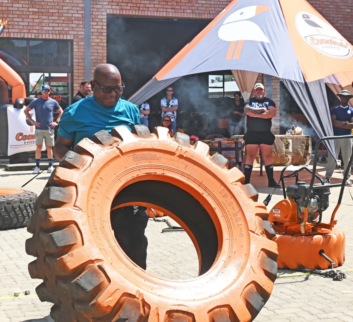 A photo of a man participating in a strong man competition at the Newcastle Coastal Hire New Store launch.