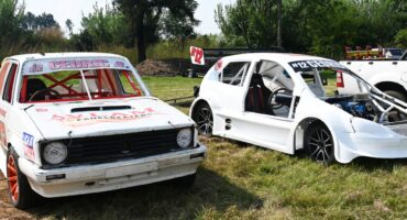 Two oval track vehicles are pictured in an open field.