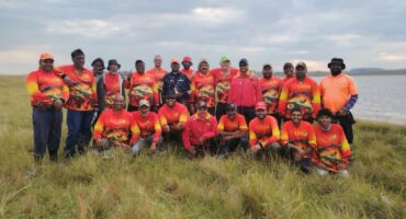 A large group of anglers pose for a photo in front of the Chelmsford Dam.