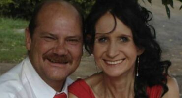 Image of a woman and man sitting next to each other, smiling.