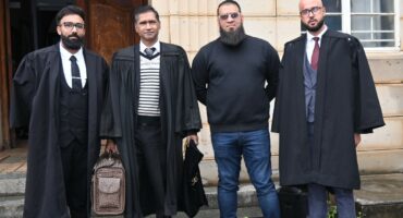Four mean dressed in black and three of them wearing legal attire stand outside the Newcastle Magistrates Court.