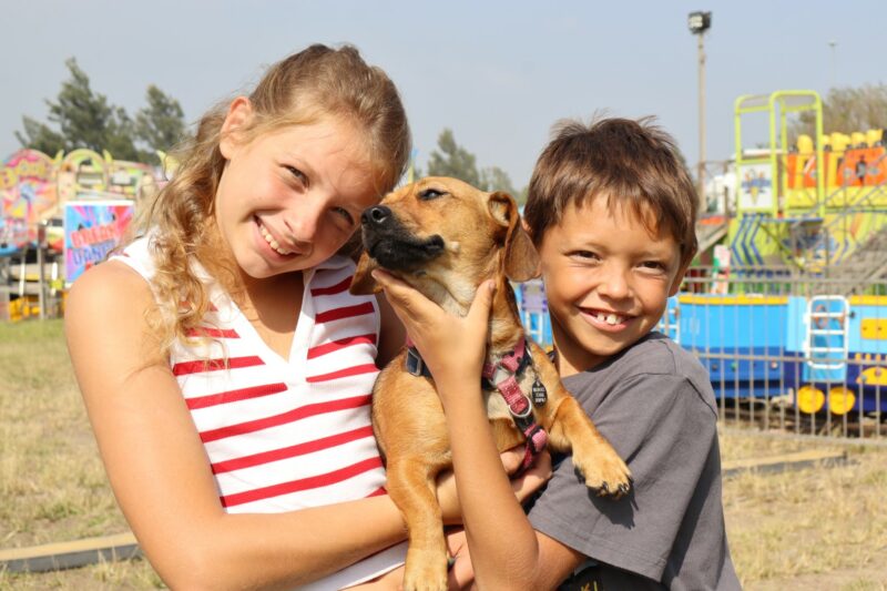 Two children are photographed with their dog at a local winter festival.